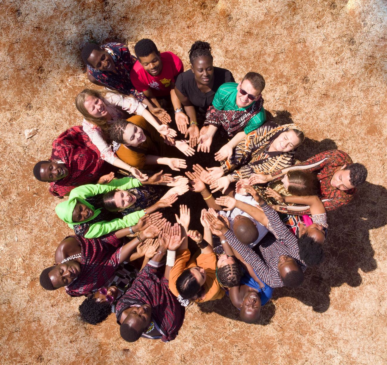 Young people from different cultures standing in a circle with their hands joined at the centre, seen from above