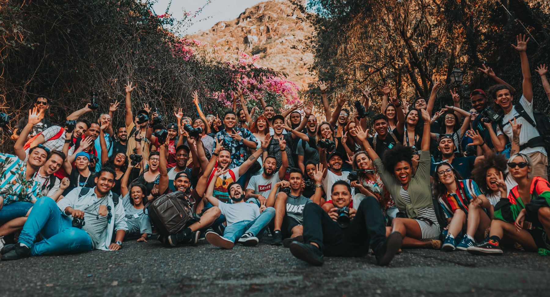 A large group of young creators with cameras waving and celebrating together